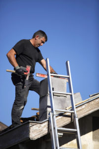 Man Building or Repairing Chimney While On Roof 