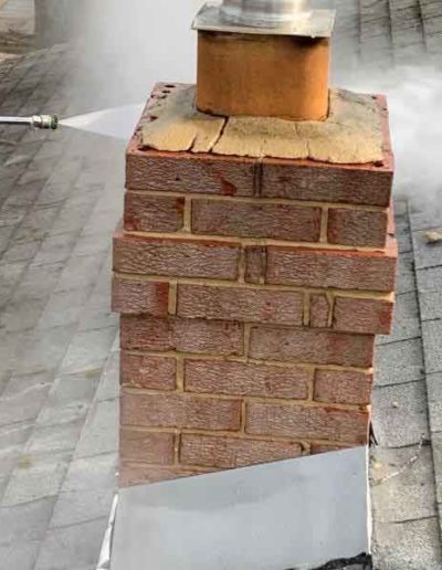 Pressure Washing Exterior Chimney to Remove Vegetation and Discoloration